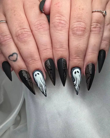 Long black stiletto press-on nails with ghost and spiderweb Halloween nail art design.