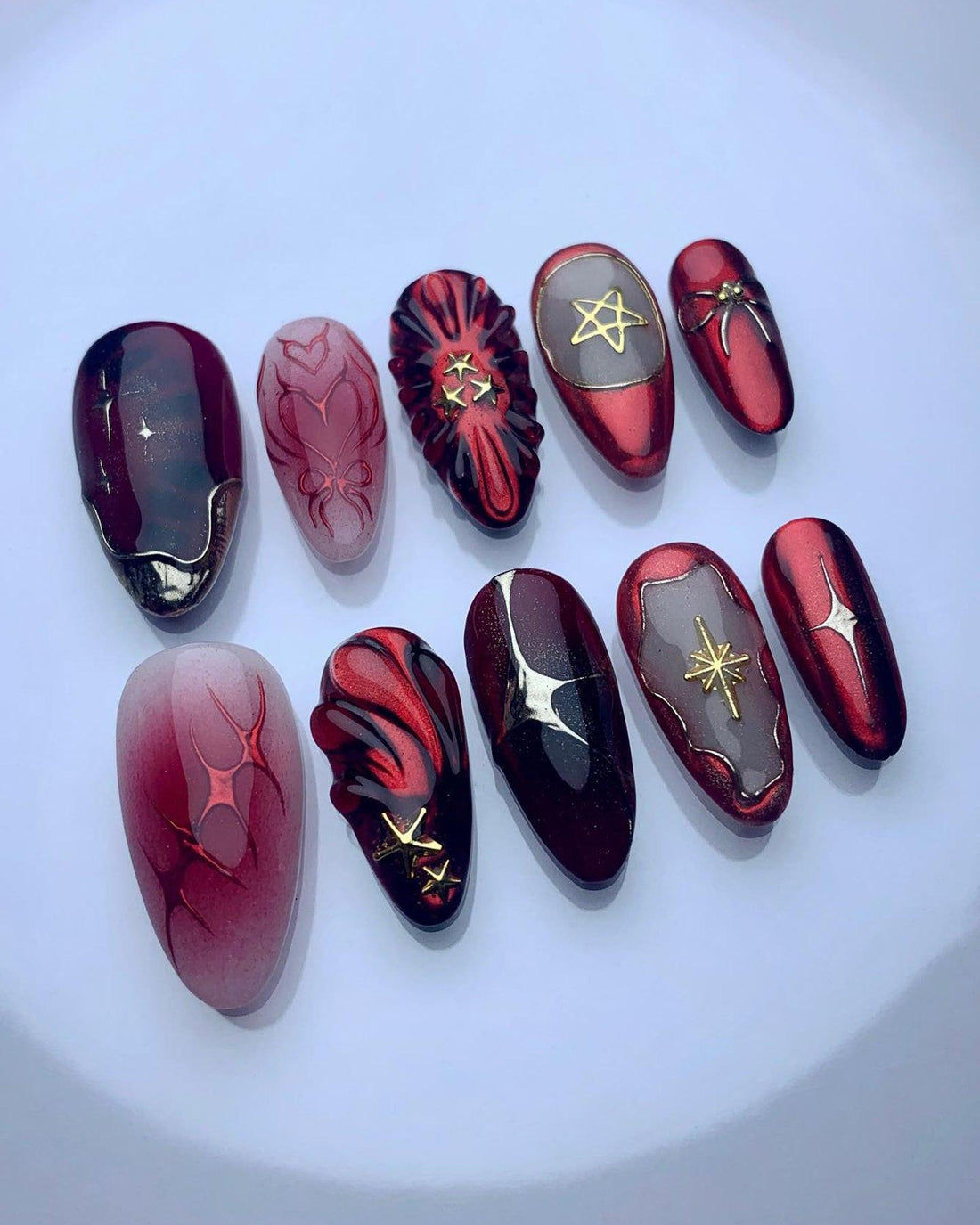 Red and black custom press-on nails with gold star and geometric designs, handmade and reusable.