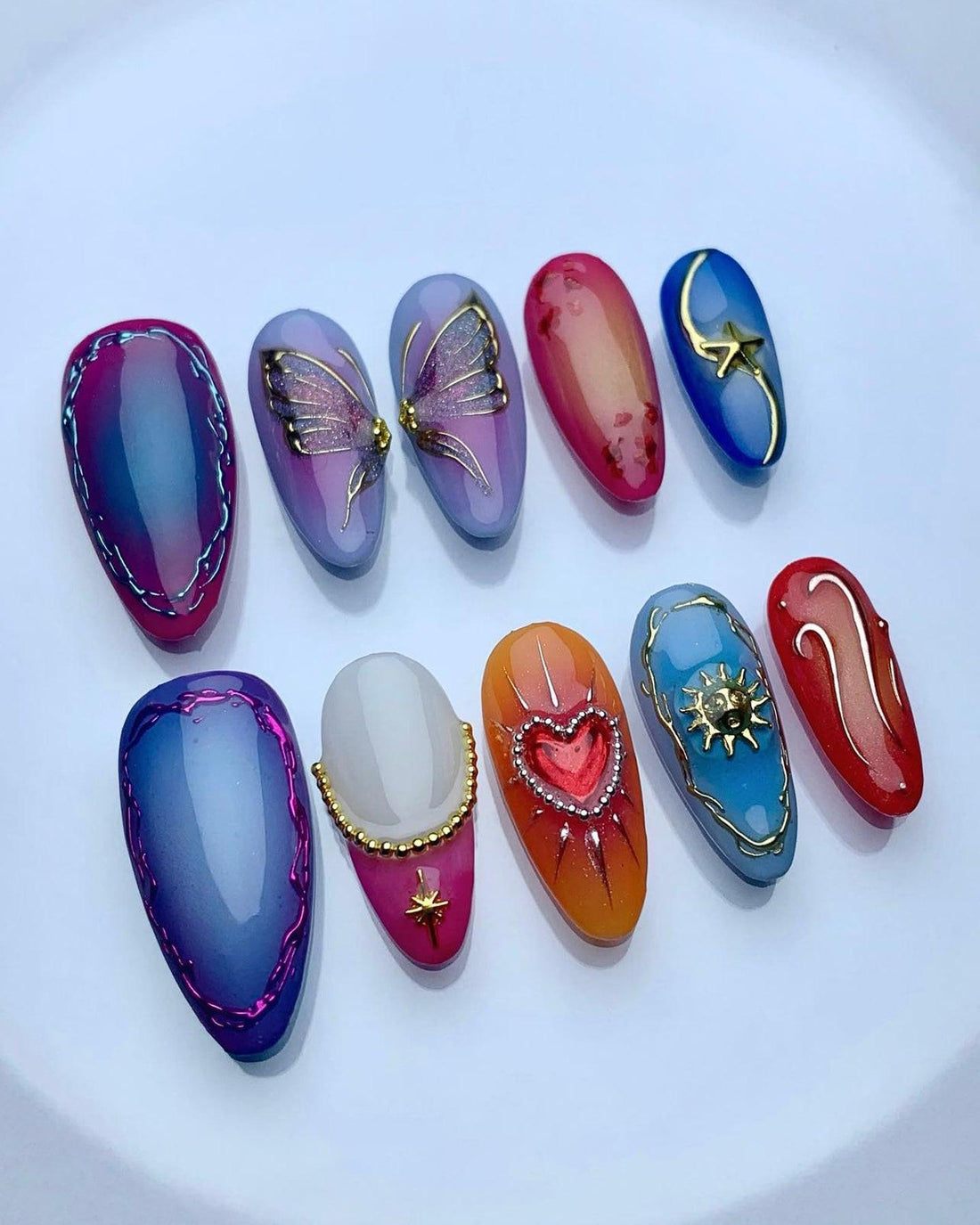 Handmade press-on nails with colorful designs, including butterfly, heart, and star art