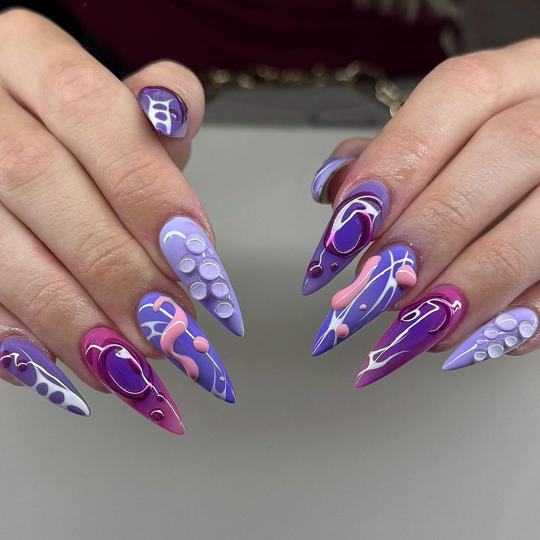 Handmade press-on nails in purple and pink swirl design with 3D accents, stiletto shape