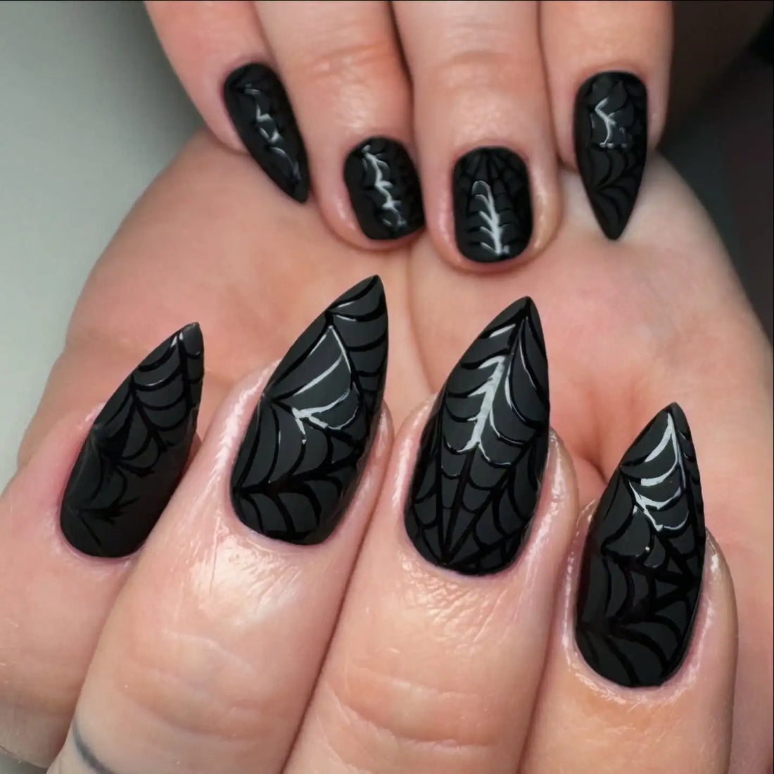 Handmade black press-on nails with glossy spider web design, stiletto and oval shapes