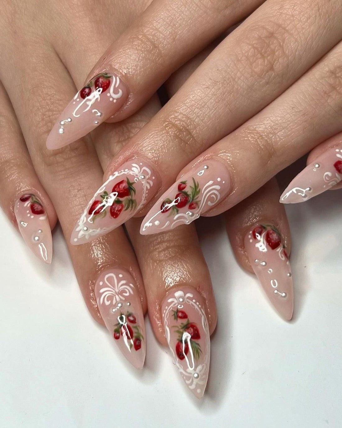 Long almond press-on nails with hand-painted red floral and white swirl designs