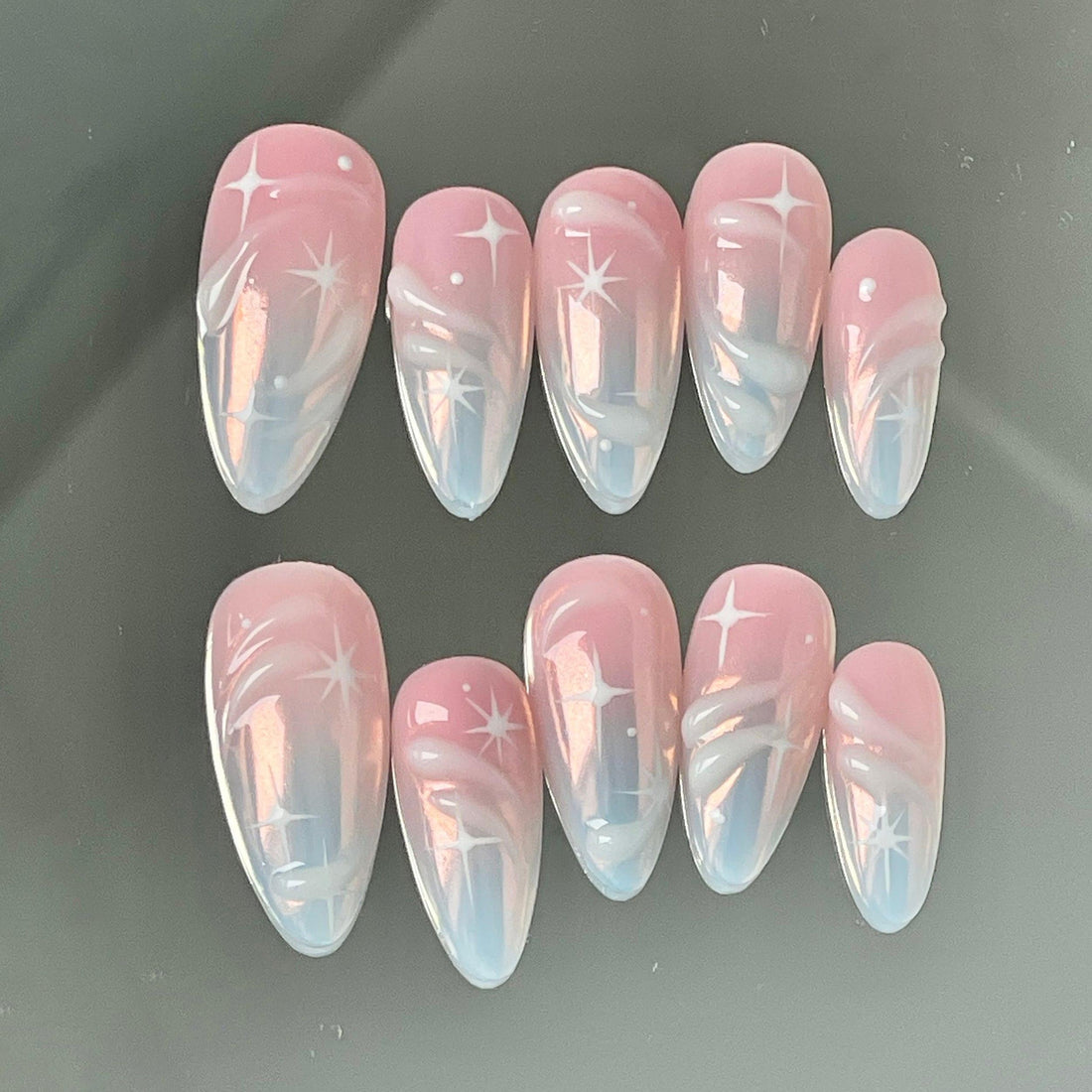 Handmade pink ombre press-on nails with white star and swirl designs, glossy finish