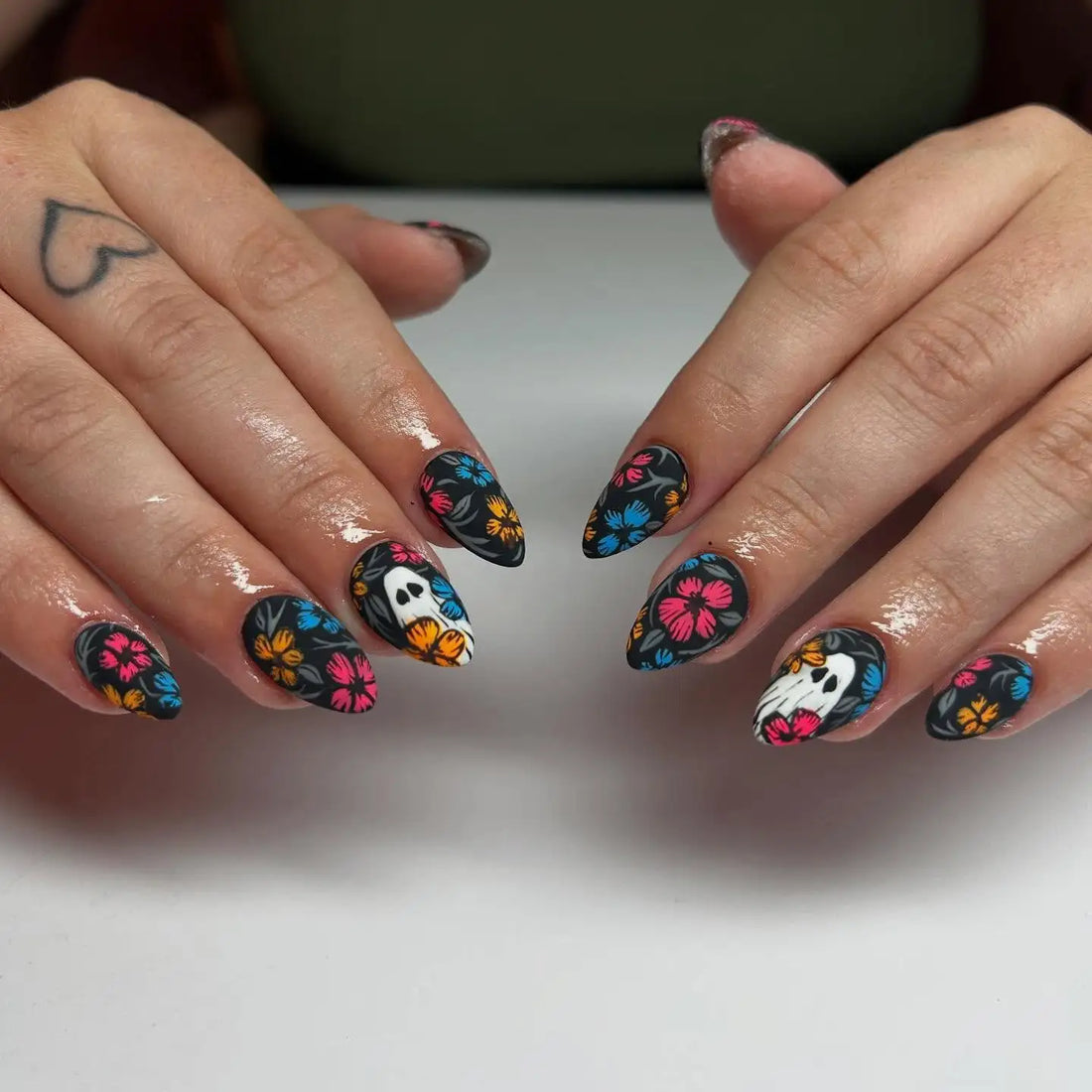 Handmade press-on nails with black base, colorful floral patterns, and skull accents.