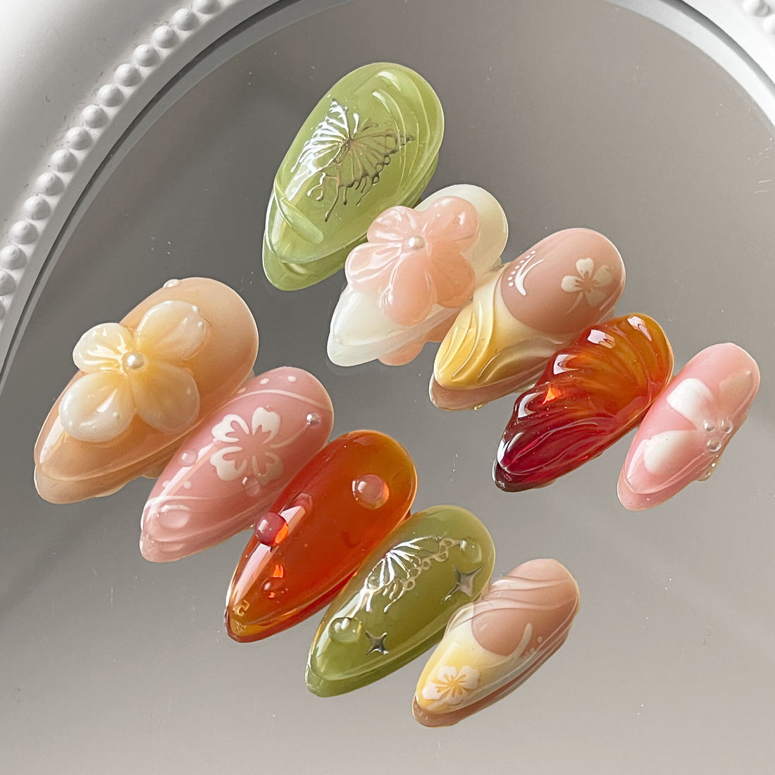 Handmade press-on nails with 3D floral designs, butterfly art, and glossy gradient colors