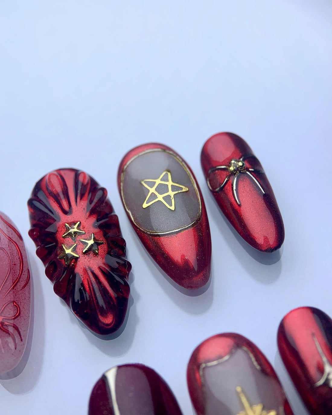 Red and black custom press-on nails with gold star and geometric designs, handmade and reusable.