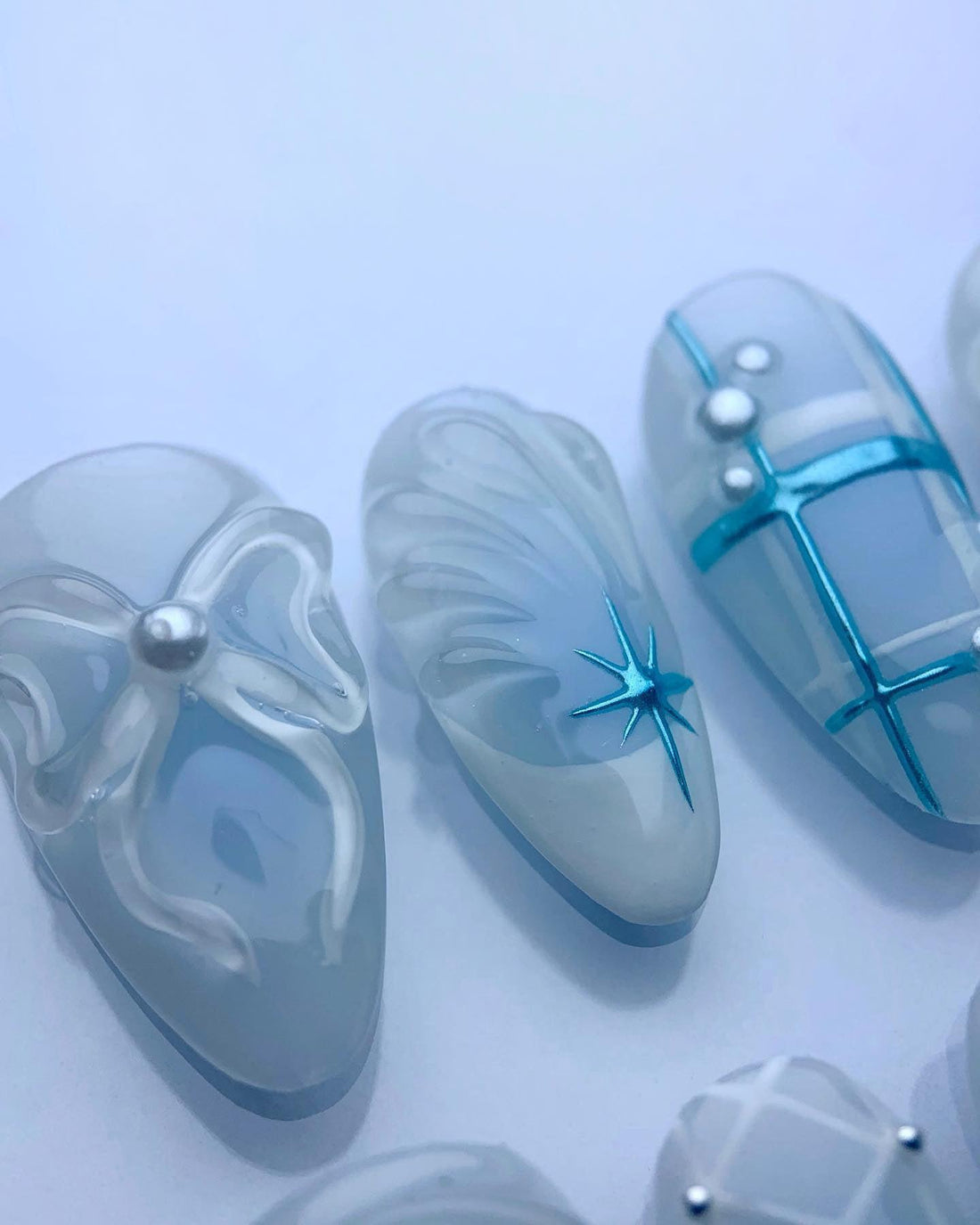 Handmade blue and white press-on nails with 3D bows, pearls, and star designs