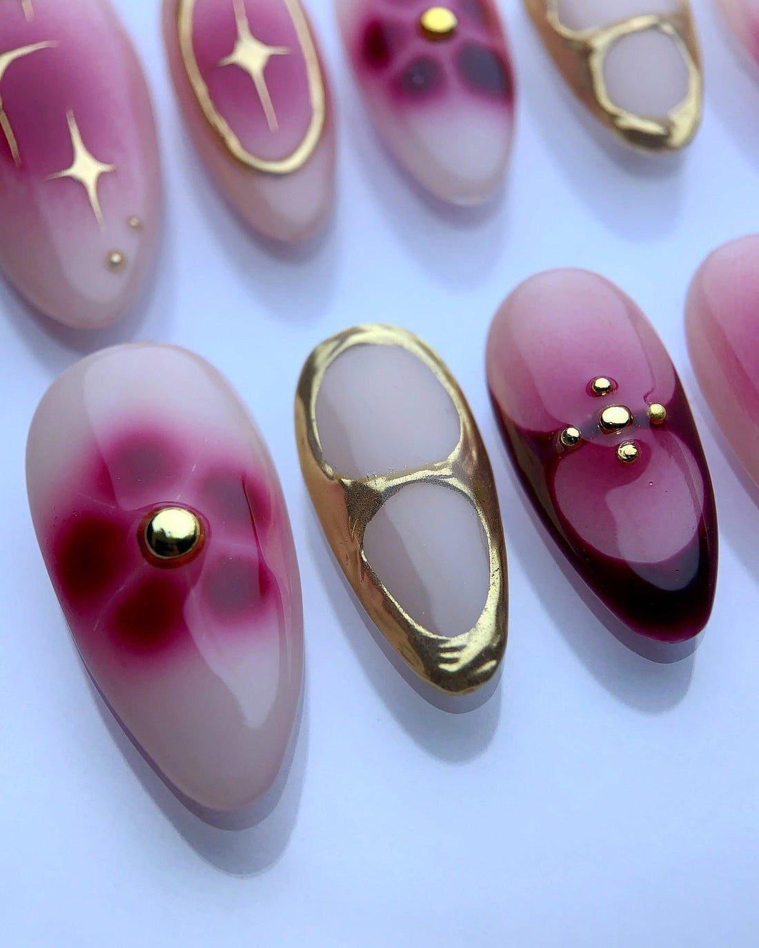 Handmade press-on nails with pink gradient, gold accents, and star designs