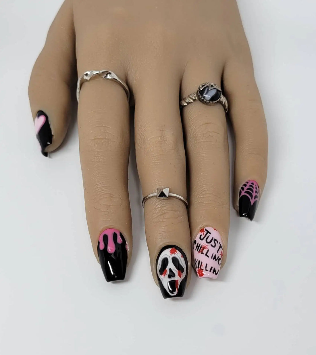 Handmade press-on nails with pink hearts, flames, spider webs, skull faces, and text design
