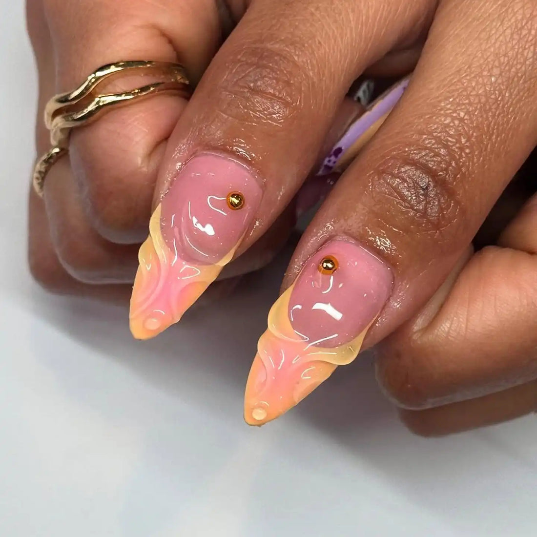 Hand with long press-on nails in pastel purple, yellow, floral and polka dot nail art.