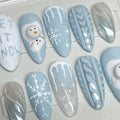 Handmade press-on nails with winter designs, snowflakes, snowmen, and blue sweater patterns