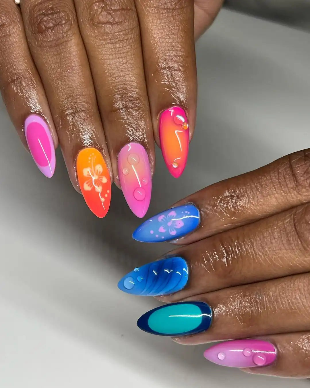 Hand with colorful handmade press-on nails, hibiscus flower art, glossy spring design