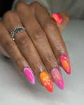 Hand with vibrant pink and orange handmade press-on nails, hibiscus floral and abstract designs