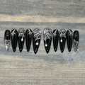Black press-on nails with white spiderweb and spider Halloween nail art