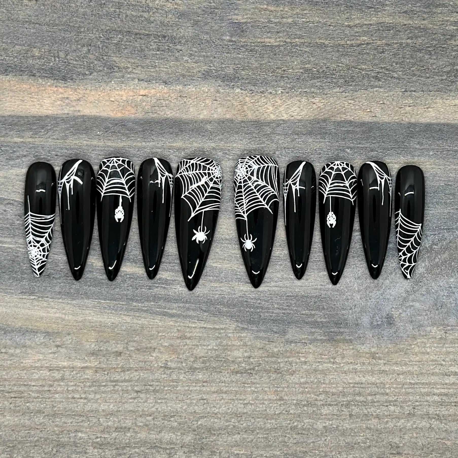Black press-on nails with white spiderweb and spider Halloween nail art