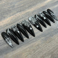 Black press-on nails with white spider web and spider designs, stiletto shape, Halloween style