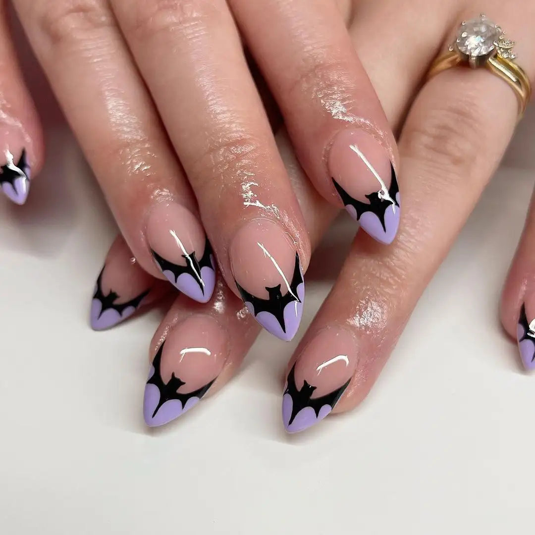 Hand with purple and black bat-themed Halloween press-on nails, pointed shape, handmade design