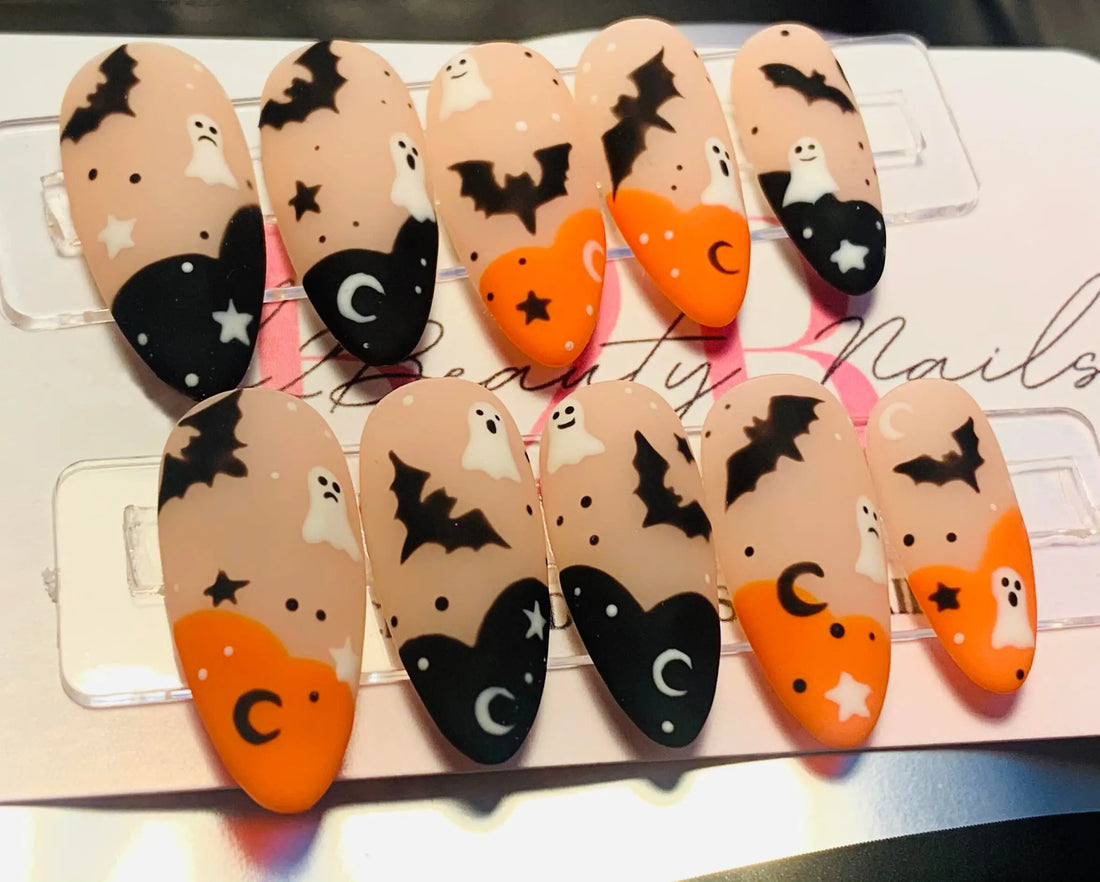 Halloween press-on nails with ghost, bat, moon, and star designs in orange and black