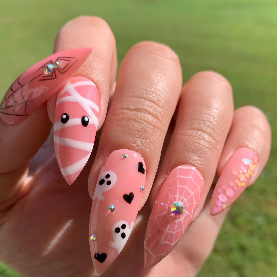 Pink Halloween press-on nails with ghost, spiderweb, mummy and glitter accents