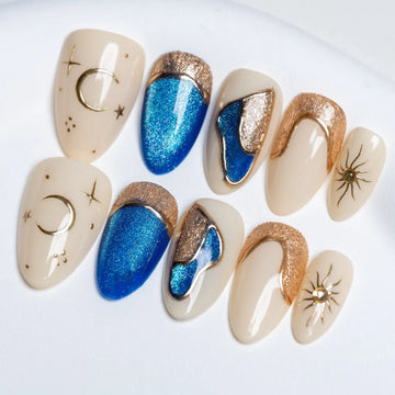 Handmade press-on nails with blue, gold, and nude celestial and sun designs