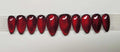 Set of glossy red cat eye stiletto press-on nails with a shimmer effect on white background