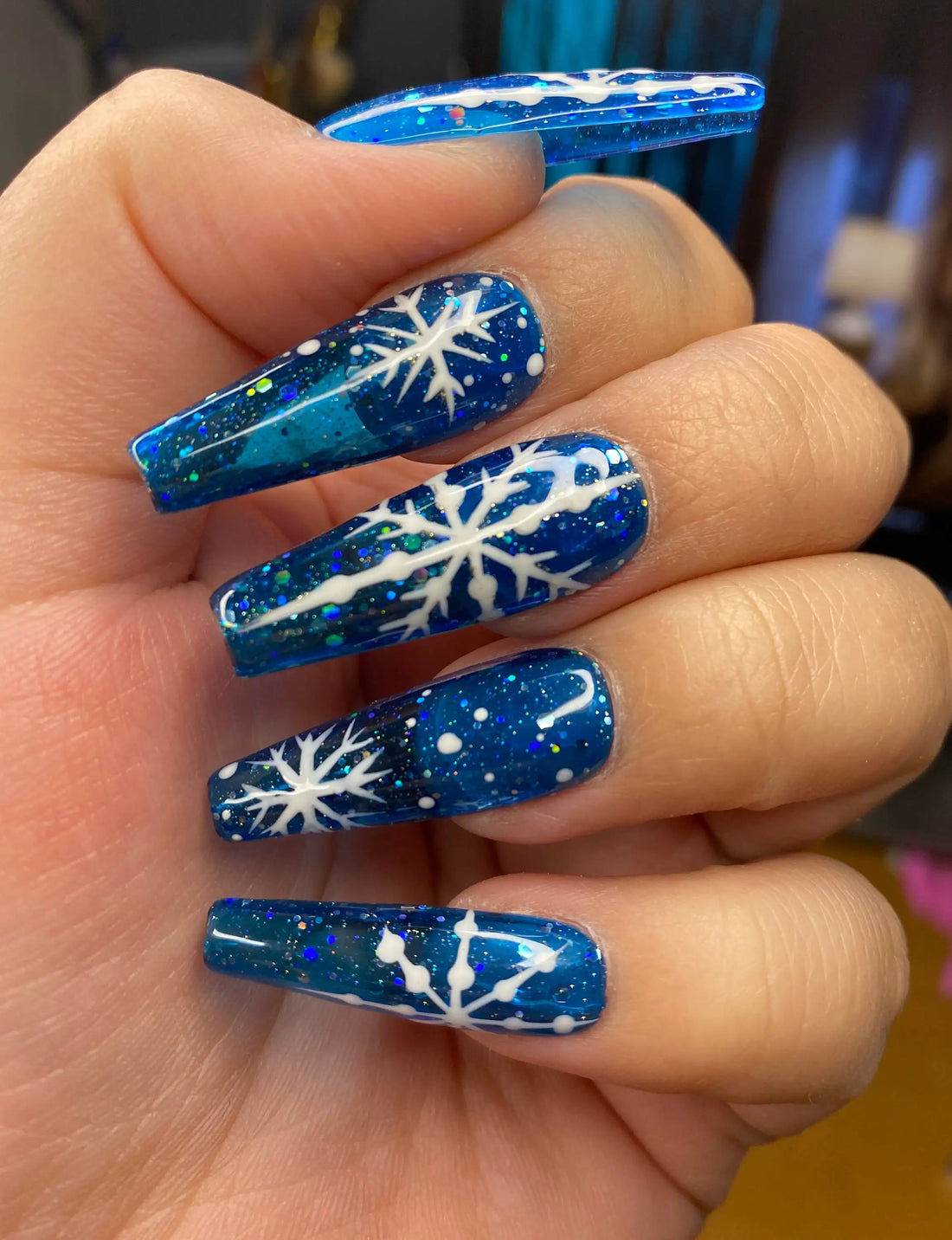 Blue glitter press-on nails with white snowflake Christmas design, long coffin shape