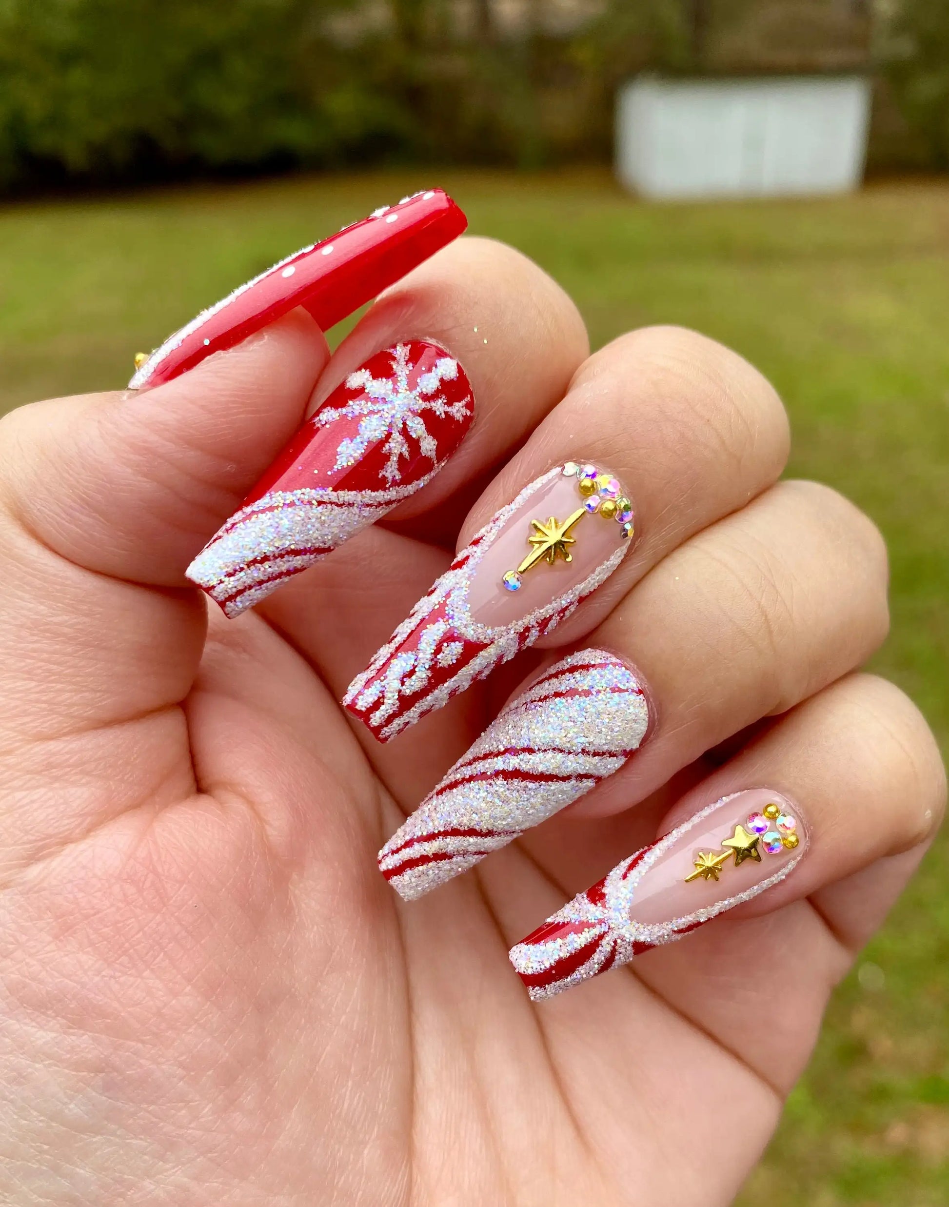 Red Christmas press-on nails with glitter, snowflakes, stars, and candy cane designs