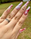 Red Christmas press-on nails with glitter snowflakes, candy cane stripes, and star rhinestones.