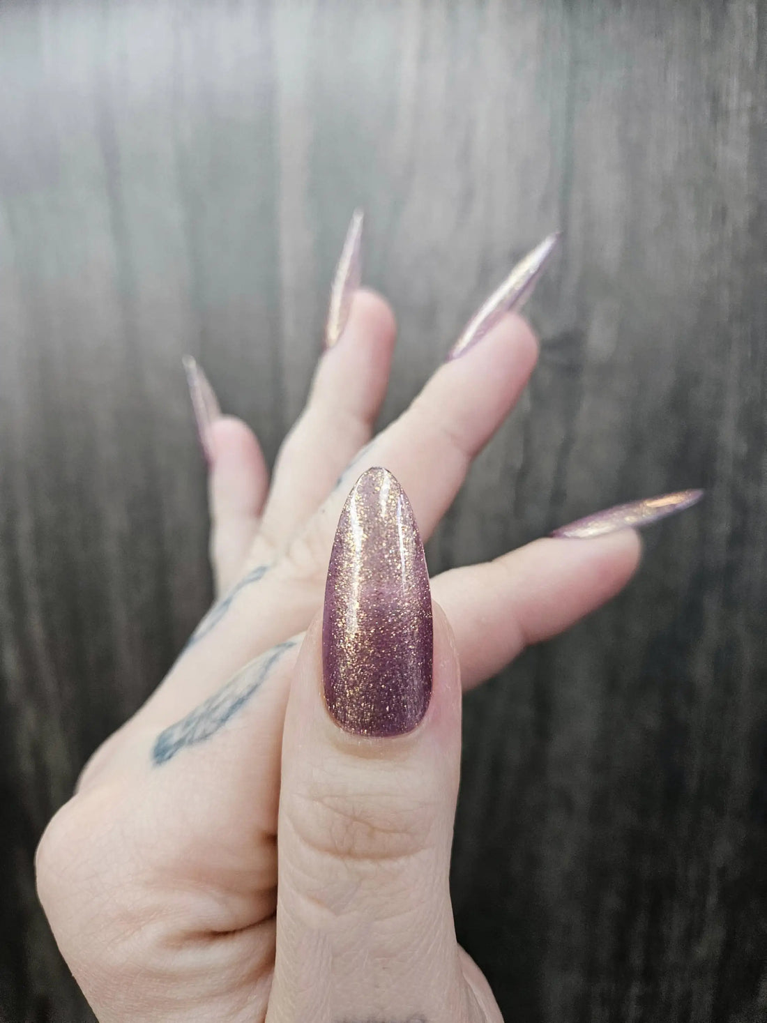 Hand with long almond-shaped purple glitter press-on nails, reusable and handmade