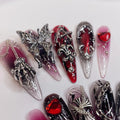 Gothic press-on nails with silver charms, red and black designs, skeleton and heart accents