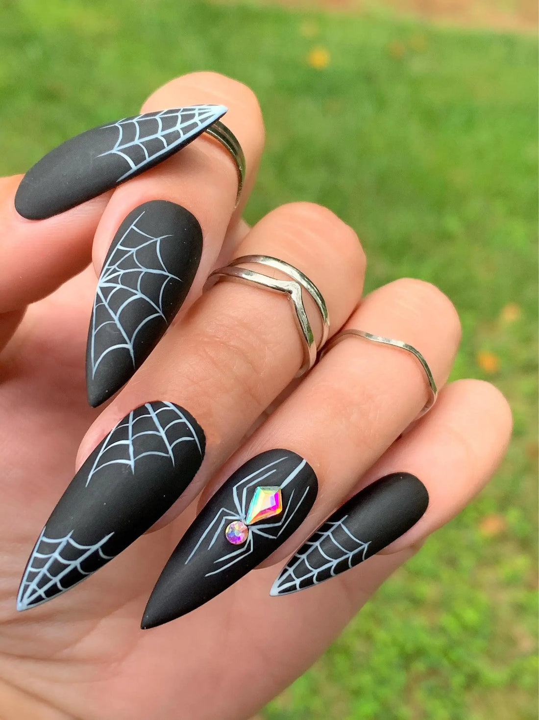 Halloween press-on nails with black matte finish, white spider webs, and sparkle gem spider design.