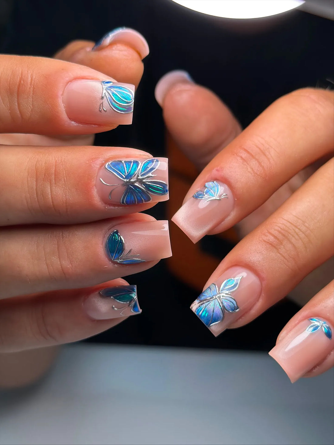 Handmade nude base press-on nails with 3D blue chrome butterfly details