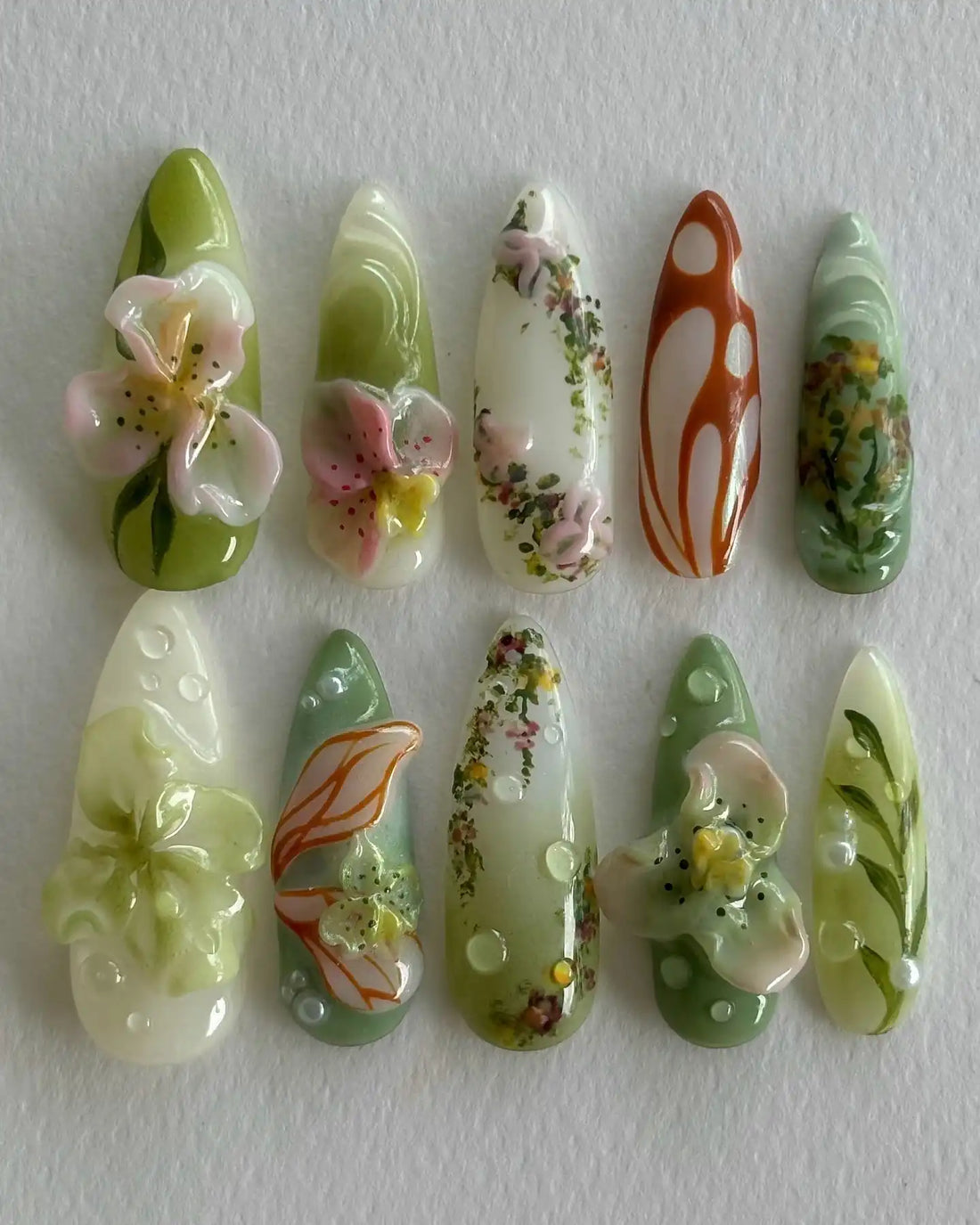Handmade press-on nails with 3D floral designs, green vines, and abstract garden accents.