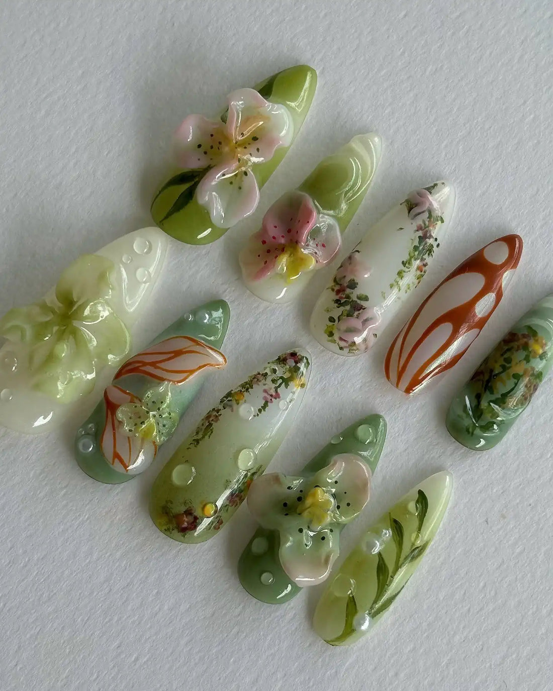 Handmade press-on nails with 3D floral designs, green vines, and abstract garden accents.