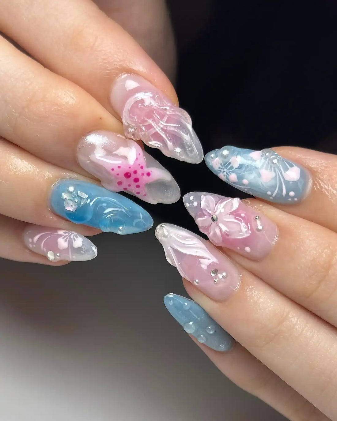 Handmade 3D floral and seashell press-on nails in pastel blue and pink with gemstone accents