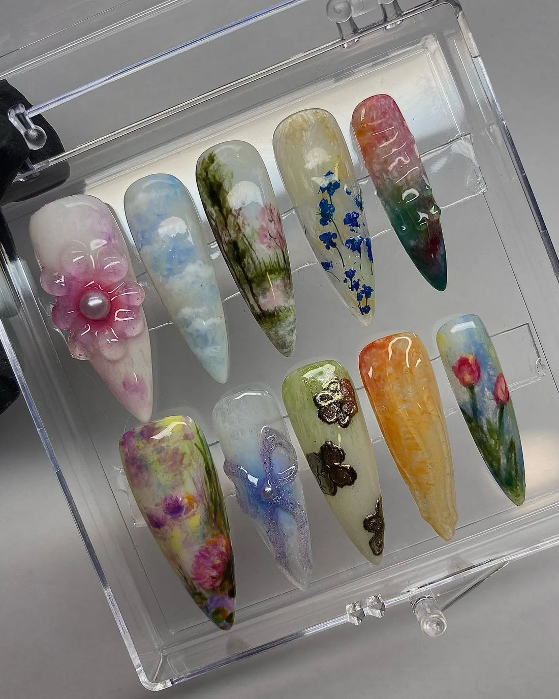 Handmade press-on nails with 3D flowers, blue sky, and watercolor landscape designs.
