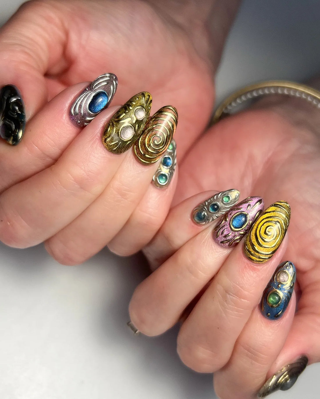 Handmade 3D metallic press-on nails with gemstone accents in chrome, gold, and colorful designs.