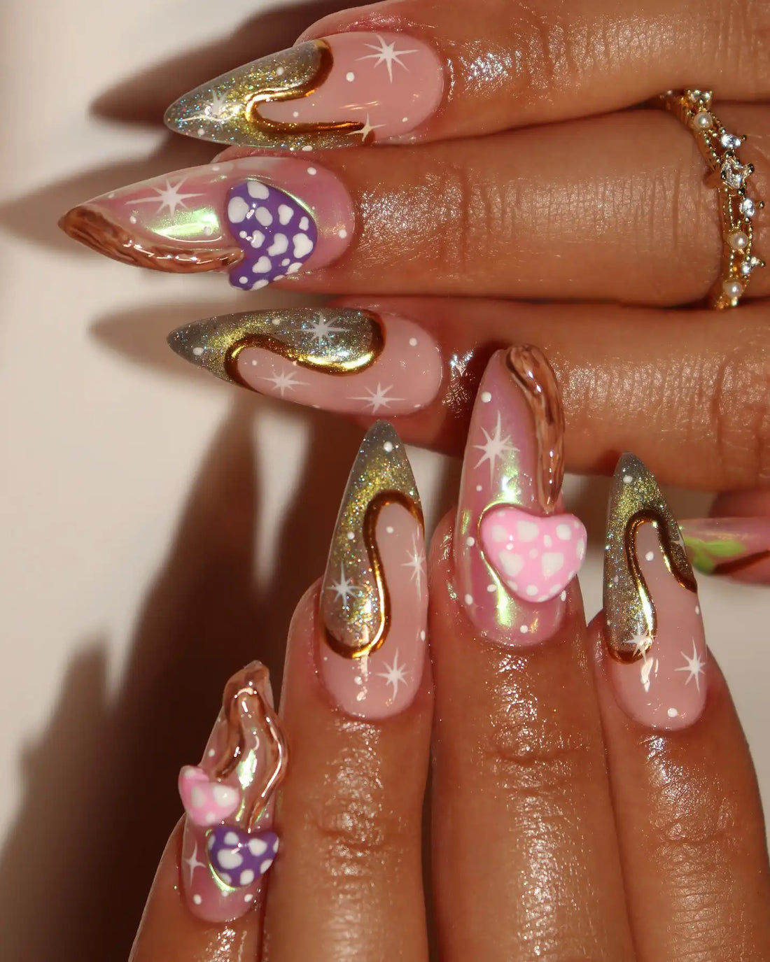 Hand with pink chrome 3D mushroom press-on nails, stardust and whimsical goth accents