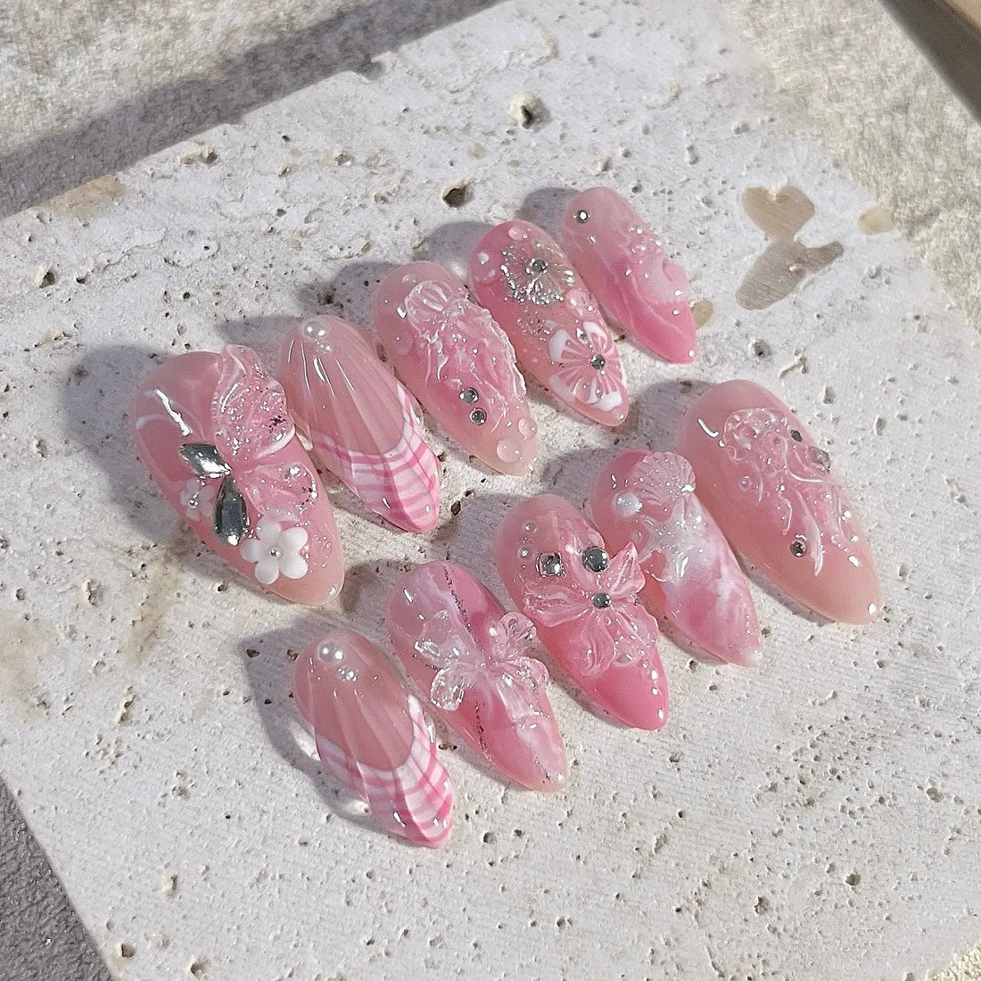 Handmade pink press-on nails with 3D butterfly, seashell, floral, and pearl gem accents