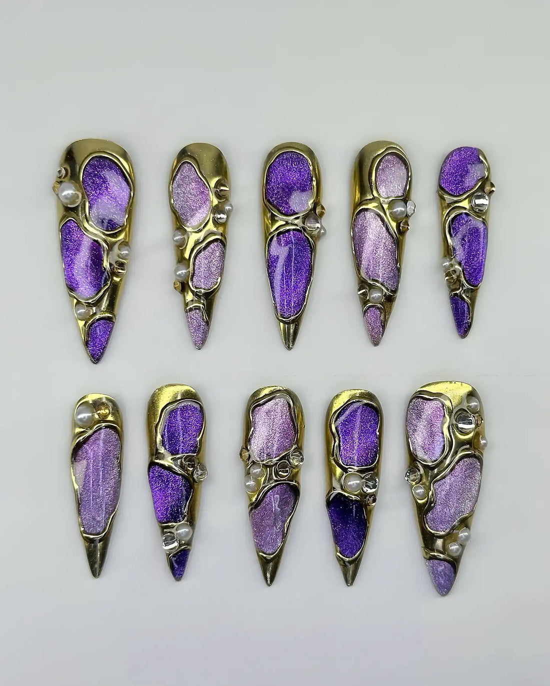 Handmade press-on nails with purple and gold chrome finish, iridescent accents, and pearls.