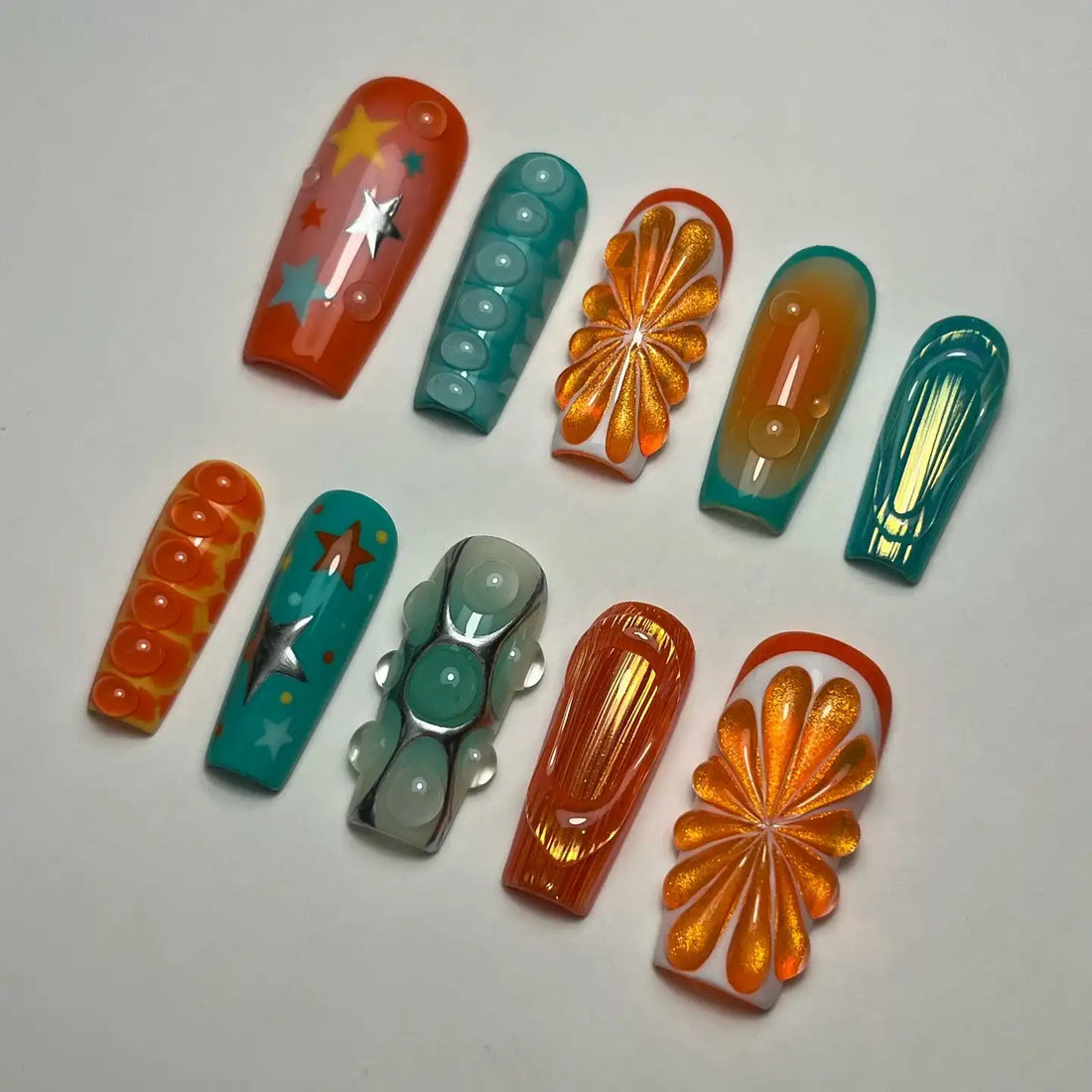 Handmade abstract press-on nails with citrus, star, teal, orange, and water drop designs