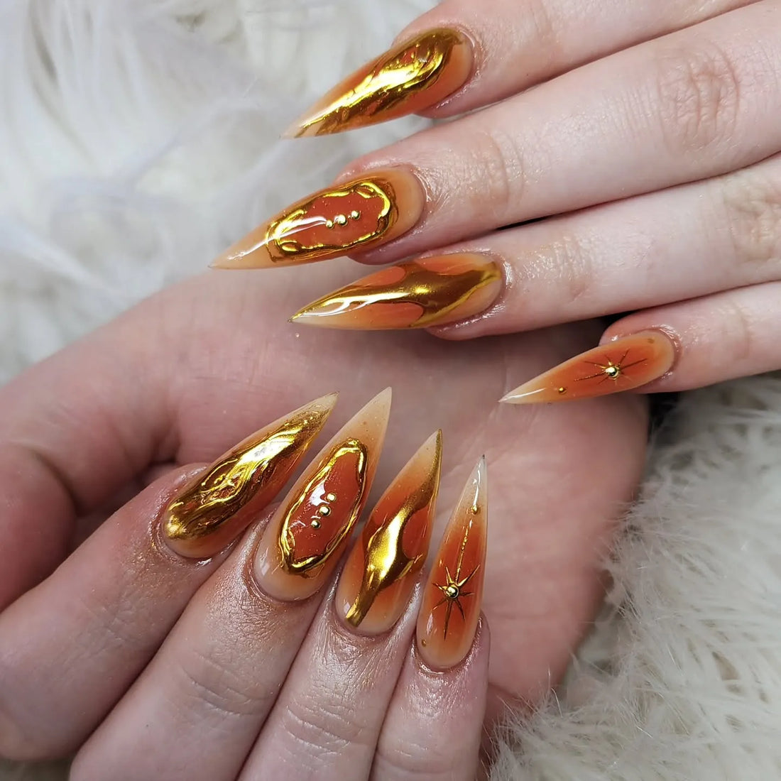 Handmade press-on nails with orange and gold chrome molten lava and starry art design.