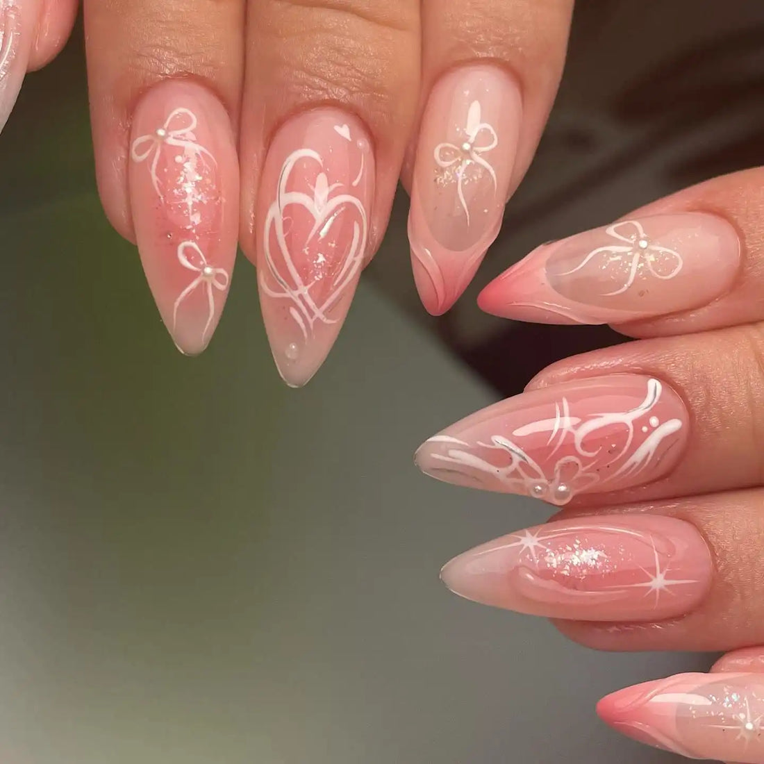 Handmade pink press-on nails with white bows, hearts, and glitter accents.