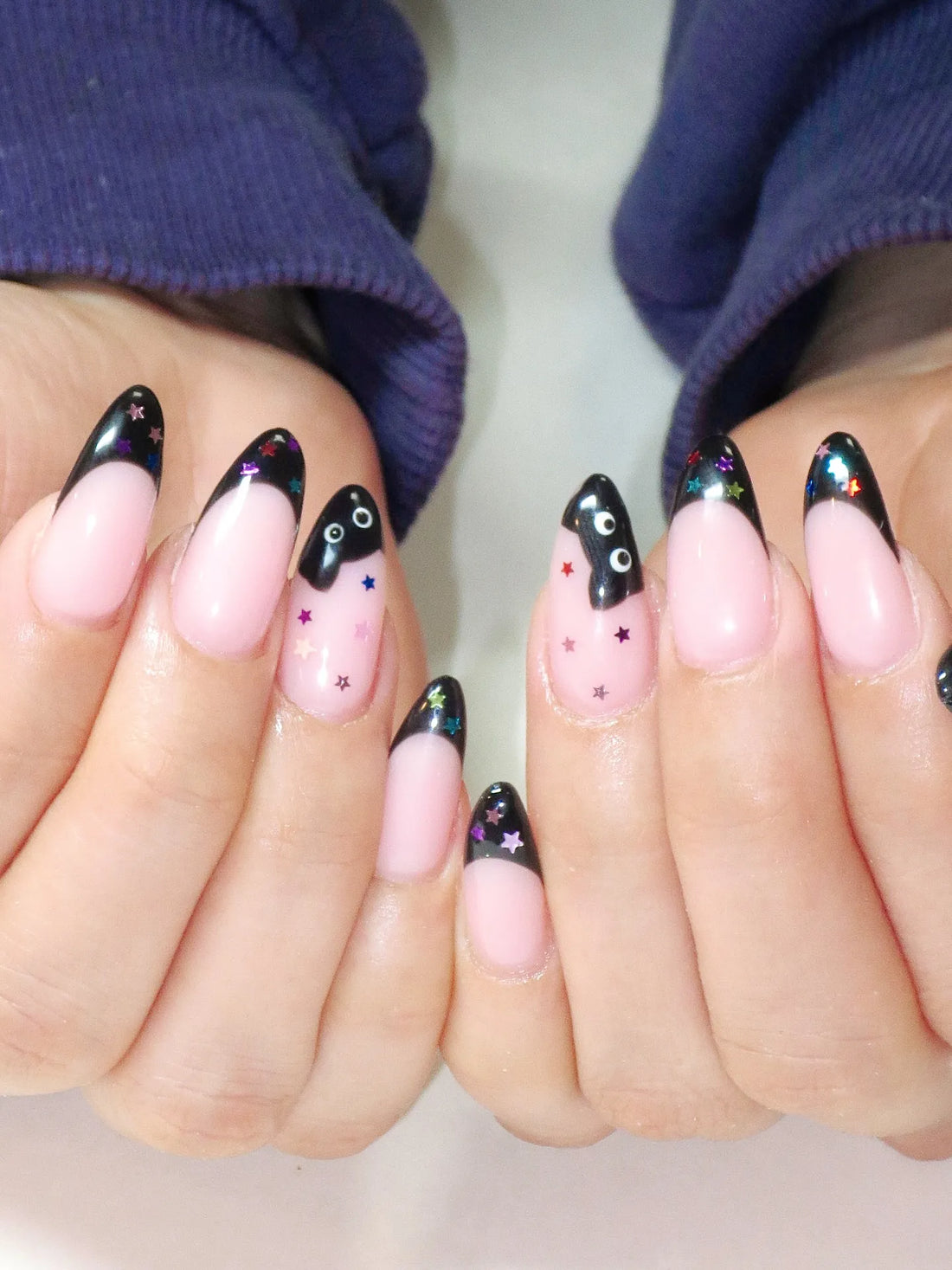 Handmade press-on nails with black French tips, colorful star accents, and black cat design.