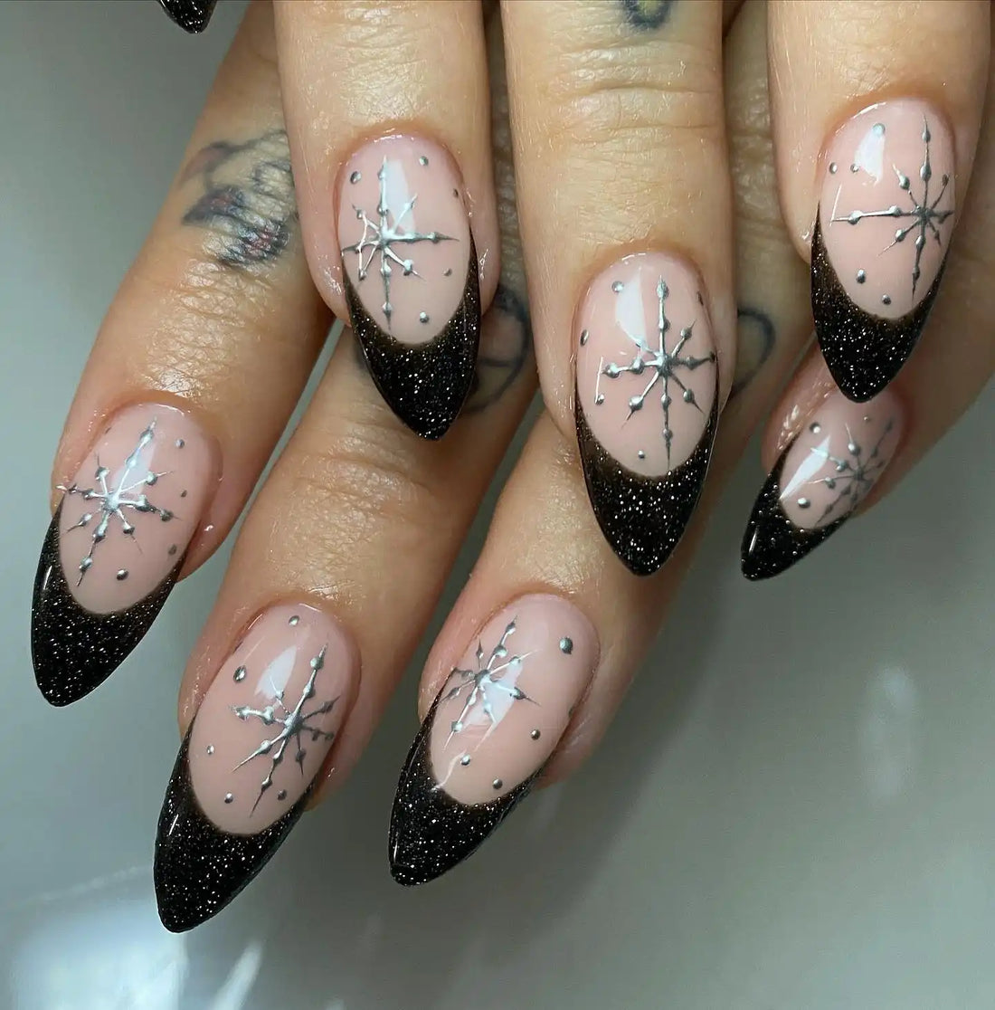 Handmade black glitter French tip press-on nails with silver starburst design