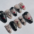 Handmade press-on nails with black and pink designs, cherry art, bows, pearls, and glitter accents.