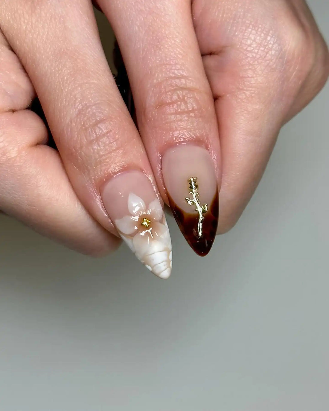 Handmade press-on nails with brown marble, gold accents, black 3D bows, and floral designs.