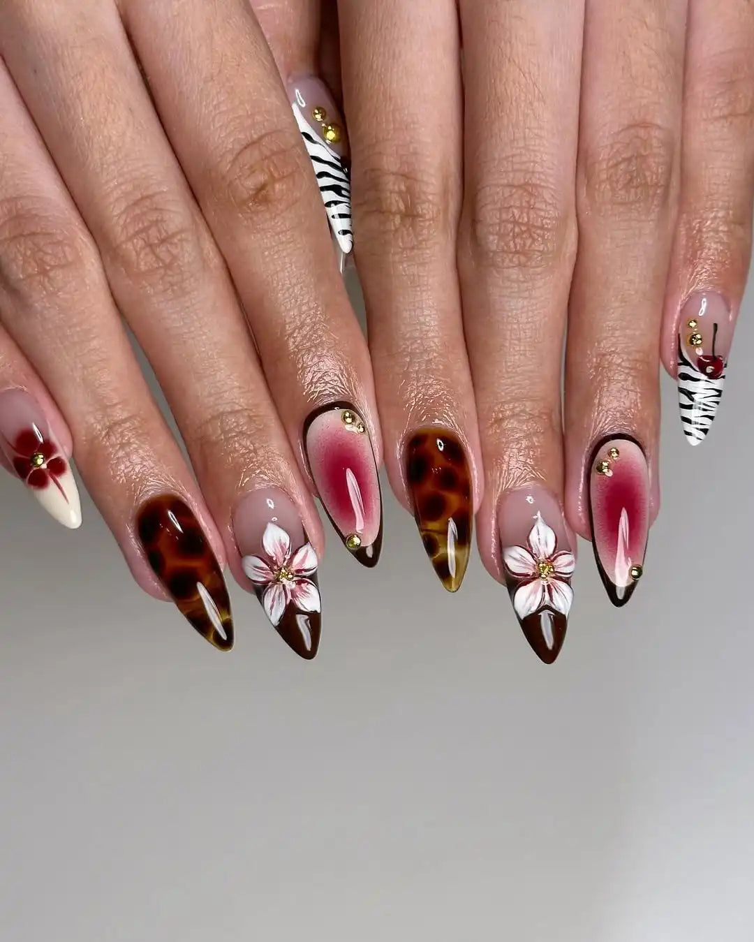 Handmade press-on nails with cherry, brown, white floral designs and gold accents.