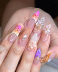 Hand with long handmade press-on nails featuring 3D butterfly and floral designs