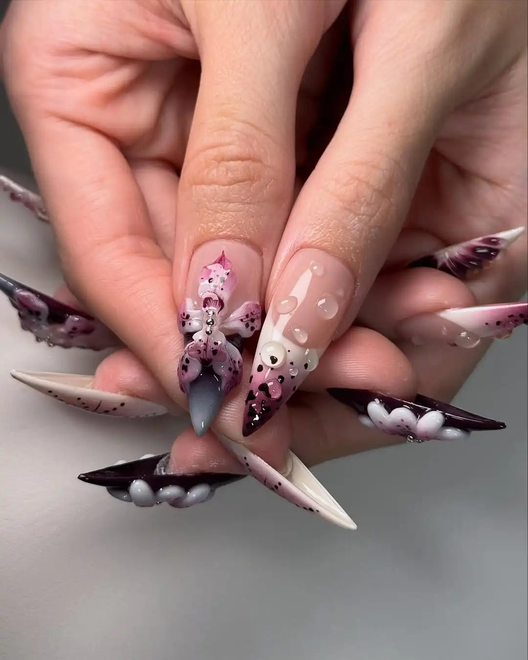 Handmade press-on nails with purple 3D floral designs and rhinestone accents